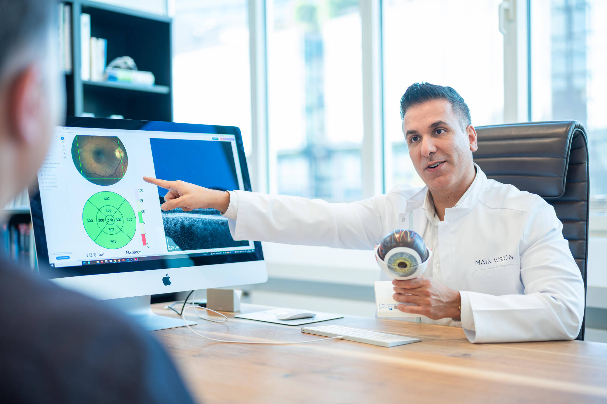 Augenvorsorge Untersuchung - Augenarzt Parviz Rafiezadeh erklärt einem Patienten das Ergebnis einer Hornhaut Untersuchung